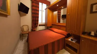 a small room with a bed and a mirror at Dama Private Rooms in Rome