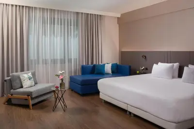 a hotel room with a large bed and a blue couch at NH Roma Villa Carpegna in Rome