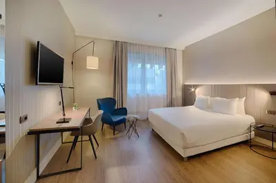 a hotel room with a white bed and a desk and a computer at NH Roma Villa Carpegna in Rome