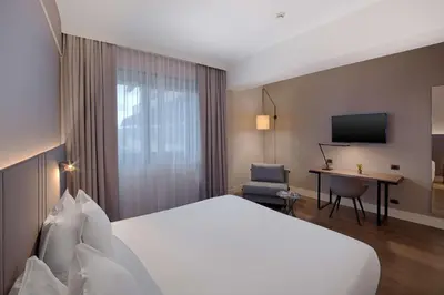 a hotel room with a large bed and a desk at NH Roma Villa Carpegna in Rome