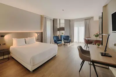 a hotel room with a white bed and a desk at NH Roma Villa Carpegna in Rome