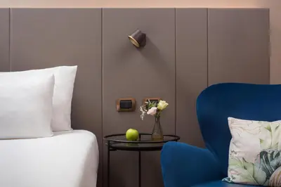 a bedroom with a bed and a table with a blue chair at NH Roma Villa Carpegna in Rome