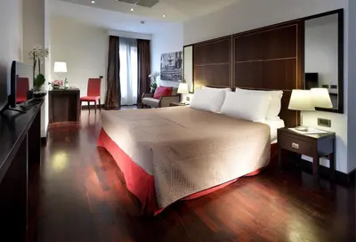 a hotel room with a large bed and a living room at Exe International Palace in Rome