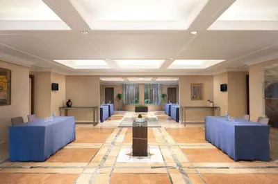 a large room with blue tables and chairs in it at Courtyard by Marriott Rome Central Park in Rome