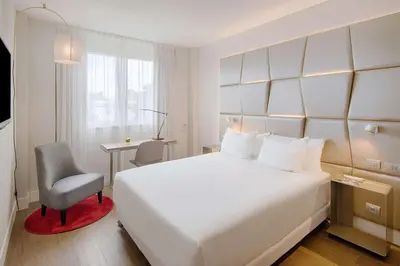 a hotel room with a white bed and a chair at NH Collection Roma Centro in Rome