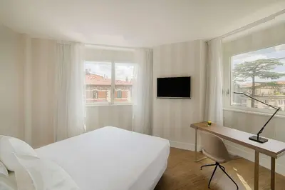 a bedroom with a bed and a desk with a computer at NH Collection Roma Centro in Rome
