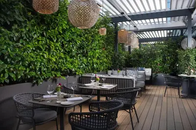 a restaurant with tables and chairs and plants at NH Collection Roma Centro in Rome