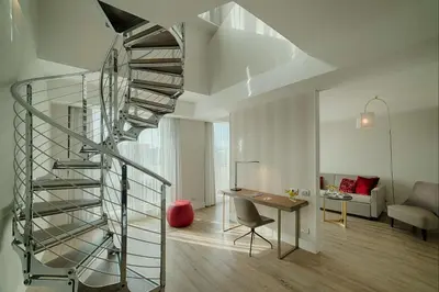 a spiral staircase in a living room with a desk at NH Collection Roma Centro in Rome