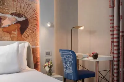 a bedroom with a bed and a blue chair next to a desk at nhow Roma in Rome