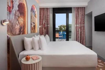 a bedroom with a large white bed and a balcony at nhow Roma in Rome