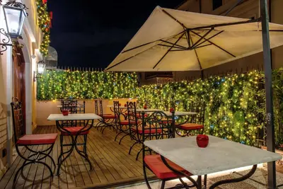 a patio with tables and chairs and a fence with lights at River Chateau Hotel in Rome