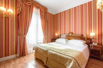 a bedroom with a large bed with red wallpaper at Gambrinus Hotel in Rome