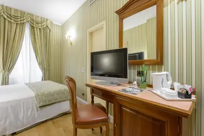 a hotel room with a bed and a desk with a television at Gambrinus Hotel in Rome