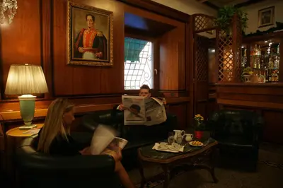 a woman sitting in a living room reading a newspaper at Hotel Bolivar in Rome