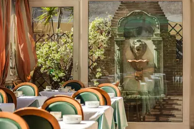 a dining room with tables and chairs and a statue at Hotel Borromeo in Rome