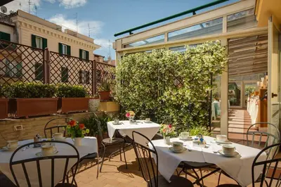 a patio with tables and chairs and a garden at Hotel Borromeo in Rome