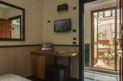 a room with a desk with a mirror and a balcony at Hotel Borromeo in Rome