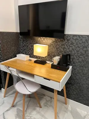 a desk with a lamp and a tv on a wall at Hotel Garda in Rome