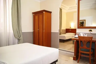 a bedroom with a bed and a desk with a chair at Hotel Hiberia in Rome