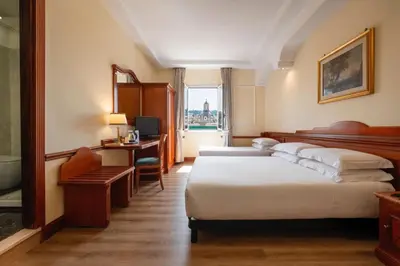 a hotel room with two beds and a desk at Hotel Hiberia in Rome