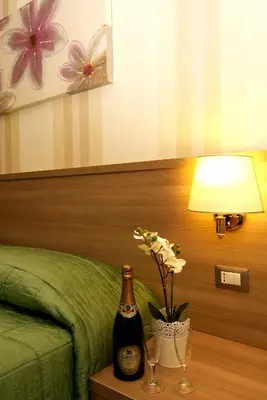 a room with a bed and a bottle of champagne and flowers at Hotel Argentina in Rome