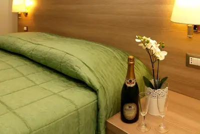 a bed with a bottle of champagne and flowers on a table at Hotel Argentina in Rome