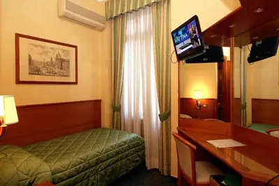 a hotel room with a bed and a desk and a mirror at Hotel Argentina in Rome