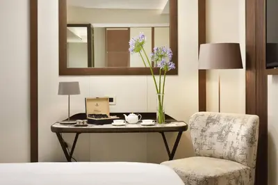 a table with a vase of flowers and a chair at FH55 Grand Hotel Palatino in Rome