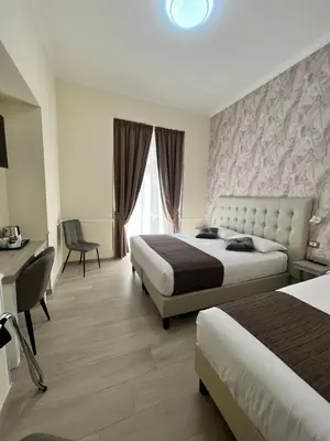 a hotel room with two beds and a desk at Hotel Le Petit in Rome