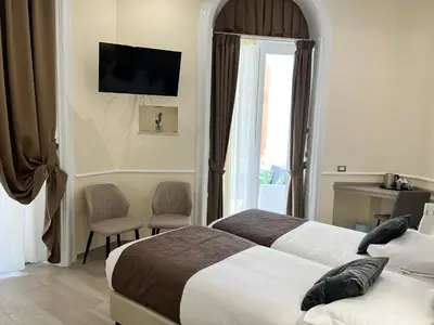 a hotel room with two beds and a window at Hotel Le Petit in Rome