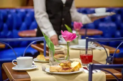 a table with a pink flower and a plate of food at Hotel Forte in Rome