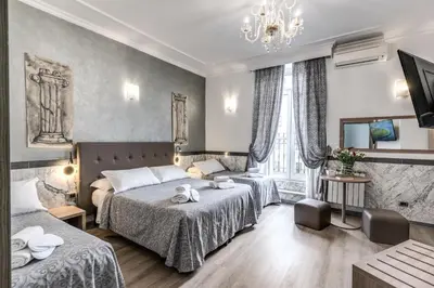 a bedroom with two beds and a chandelier at Hotel Centro Cavour Roma in Rome