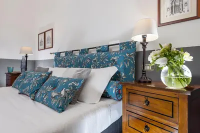 a bed with blue and white pillows and a vase on a dresser at All'Orologio in Rome