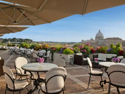 a patio with tables and chairs and a view of the city at Atlante Star Hotel in Rome