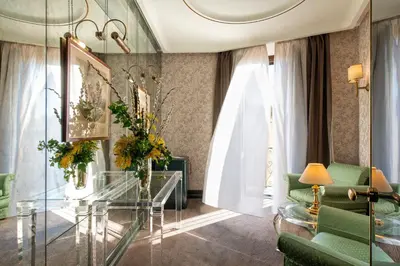 a living room with a glass table and green chairs at Atlante Star Hotel in Rome