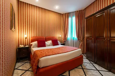 a bedroom with a large bed with red pillows at Atlante Star Hotel in Rome