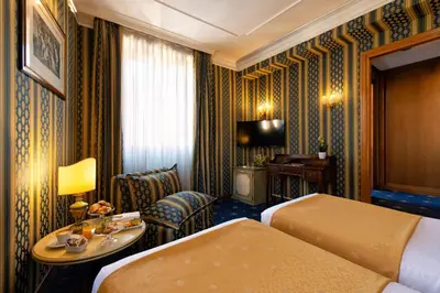 a hotel room with two beds and a chair at Atlante Star Hotel in Rome