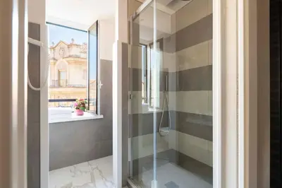 a glass shower in a bathroom with a window at Atlante Star Hotel in Rome