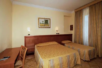 a hotel room with two beds and a desk at Hotel Meridiana in Rome