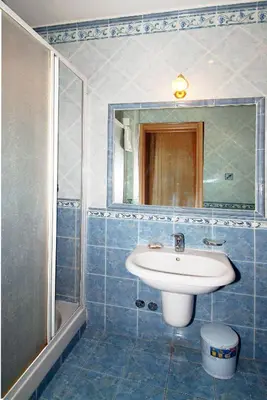 a blue tiled bathroom with a sink and a shower at Hotel Meridiana in Rome
