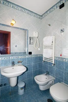 a blue tiled bathroom with a sink and a toilet at Hotel Meridiana in Rome