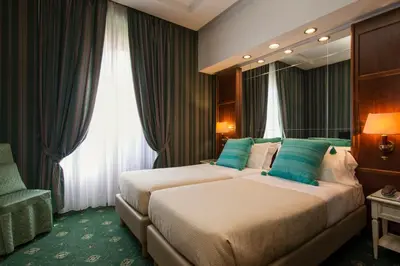 a hotel room with two beds and a chair at Atlante Garden Hotel in Rome