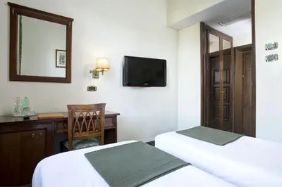a bedroom with two beds and a desk and a mirror at Grand Hotel Gianicolo in Rome