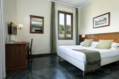 a bedroom with a bed and a desk and a window at Grand Hotel Gianicolo in Rome