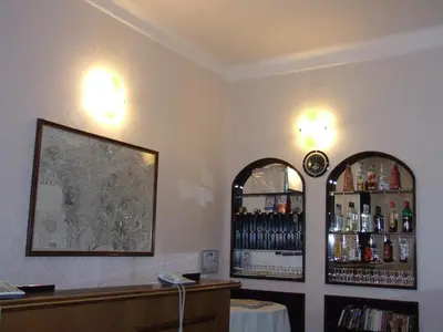 a bar with two mirrors and a shelf of wine bottles at Hotel Texas in Rome