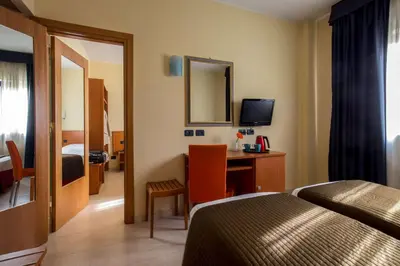 a hotel room with a bed and a desk with a mirror at Best Western Blu Hotel Roma in Rome