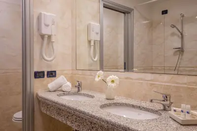 a bathroom with two sinks with a vase of flowers at Best Western Blu Hotel Roma in Rome