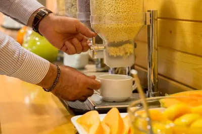 a person making a cup of coffee in a mixer at Best Western Blu Hotel Roma in Rome