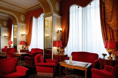 a waiting room with red chairs and tables and curtains at Bettoja Hotel Massimo d'Azeglio in Rome
