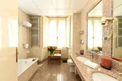 a bathroom with two sinks and a tub and a toilet at Bettoja Hotel Massimo d'Azeglio in Rome
